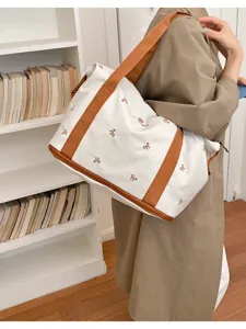 Large capacity travel duffel bag with cute bow embroidery and sturdy brown canvas straps.