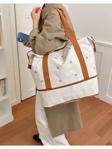 Large capacity canvas travel duffel bag with stylish bow embroidery and brown straps for women.
