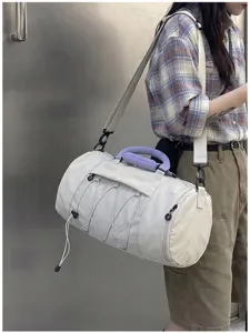 Detailed view of the cylindrical sports duffel bag with a front mesh pocket and purple handle.