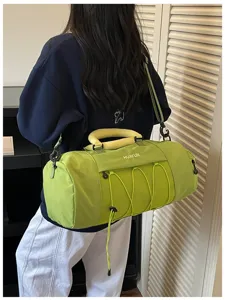 Green large capacity gym duffel bag with yellow handle and mesh pocket detail in use.