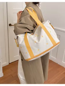 Detail view of the large canvas travel bag with yellow straps and cute bow embroidery.