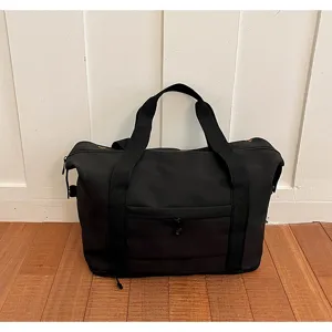 Black travel duffel bag detail view, durable fabric gym bag with sturdy handles and pocket.