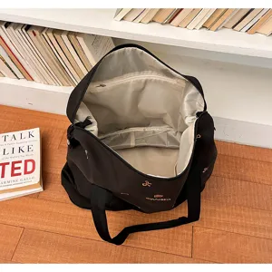 Black canvas travel tote bag open interior view showing large storage capacity and zipper pockets.