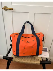 Large orange duffel travel bag with blue straps and bow print details for weekend trips.
