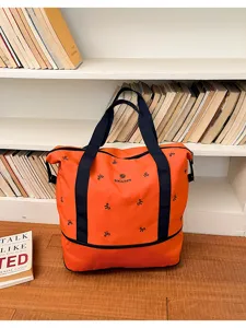 Orange large capacity travel bag with blue straps and bow embroidery, detailed view.