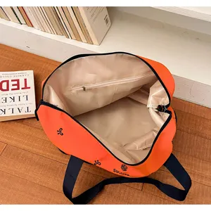 Orange travel duffel bag detail showing interior lining, zipper pocket, and durable fabric.