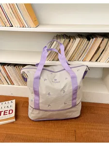 Large capacity canvas travel bag with purple handles and bow embroidery for women storage.