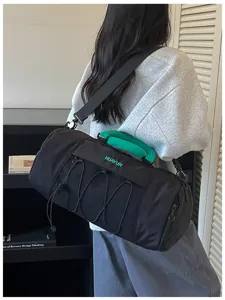 Black sports fitness duffel bag with green handle and elastic cords for travel use.