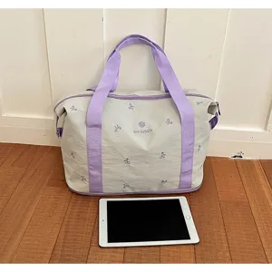 Detail view of large capacity travel duffel bag with purple handles and bow stitches.