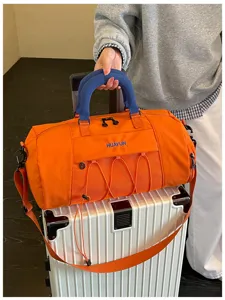 Detailed shot of orange travel gym duffel bag with blue handles, mesh pocket, and shoulder strap.