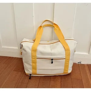 Canvas travel duffel bag detail showcasing yellow webbing handles and front zipper pocket.