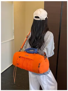 Detailed view of the orange gym duffel bag featuring blue handle, bungee cord, and large capacity.