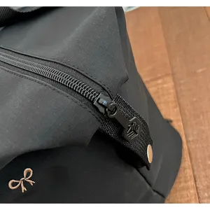 Close-up detail shot of black travel duffel bag showcasing zipper quality and bow embroidery.