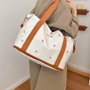 Large capacity canvas travel duffel bag with stylish bow embroidery and brown straps for women.
