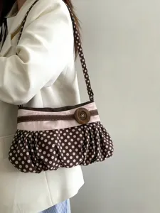 Close-up detail shot of the brown polka dot underarm bag with wooden button and ruched texture.