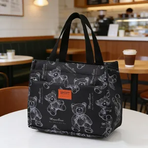 Detail view of the black insulated lunch bag with cute bear pattern, sturdy handles and front pocket.