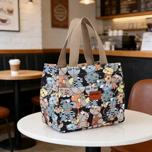 Canvas lunch bag detail showcasing cute cat pattern print, durable handles and small front pocket.