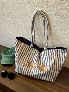 Detail view of striped canvas tote bag with gold letter print, casual chic shoulder bag.