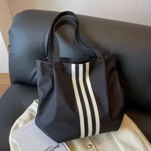 Detailed view of the stylish black tote bag with white vertical stripes and sturdy straps.