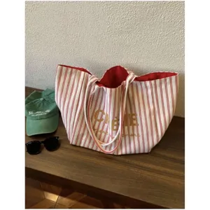 Detail shot of red white striped canvas tote bag with red interior and elegant gold lettering.