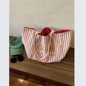 Red and white striped canvas tote bag with red lining and elegant golden typography accent.