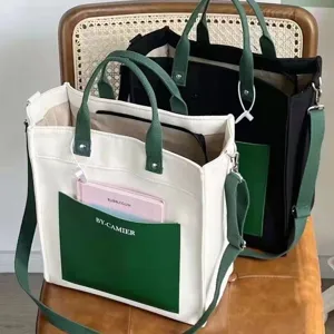 Detailed view of the canvas tote bag with contrast green pockets and adjustable shoulder strap.