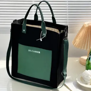 Black canvas tote bag with green shoulder strap, casual daily handbag for students and office workers.