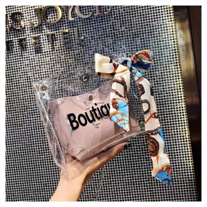 Transparent PVC crossbody jelly bag with pink inner pouch and elegant printed silk scarf.