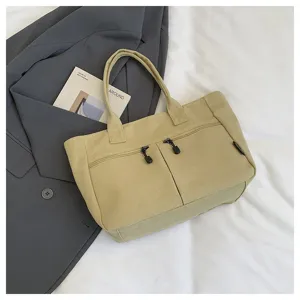Detailed view of the casual canvas tote bag featuring dual handles and front zippered pockets.