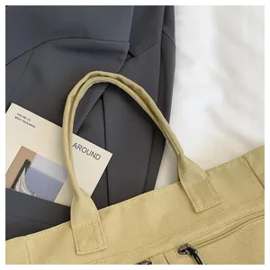 Detail view of the khaki canvas tote bag, showing the durable fabric texture and zipper pocket.