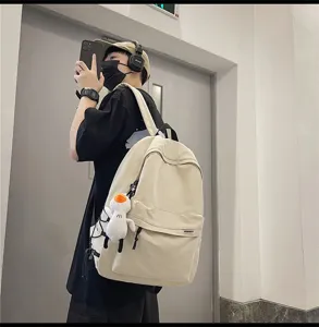Casual lifestyle detail shot of a large-capacity beige canvas student backpack with daily wear.