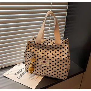 Detail shot of black and white polka dot canvas tote bag with front pocket and cute charms.