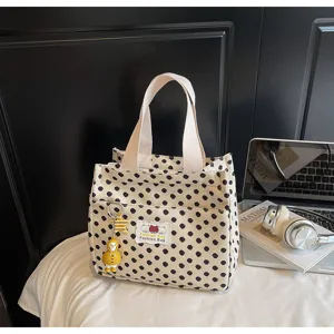 Canvas tote bag detail view, showing cute polka dot pattern, fabric handles, and duck charm.