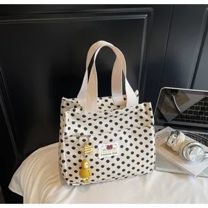 Black and white polka dot canvas tote bag with front pocket and cute duck keychain accessory.