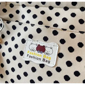 Canvas tote bag detail view, showing cute bear label and black polka dot fabric texture.