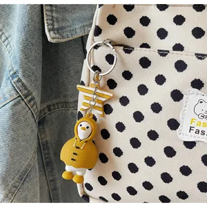 Canvas handbag detail view featuring cute duck keychain and classic polka dot fabric material.