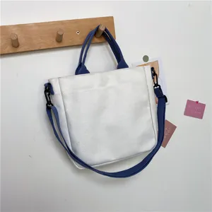 Stylish casual white canvas tote bag with blue handles and adjustable strap for women students.