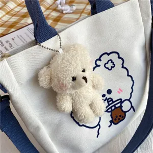 Cute canvas tote bag detail showing cute plush bear pendant and printed cartoon design.