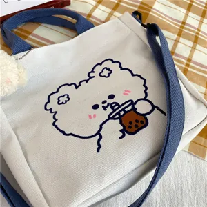 Canvas tote bag detail view showing cute cartoon bear graphic and durable blue strap.