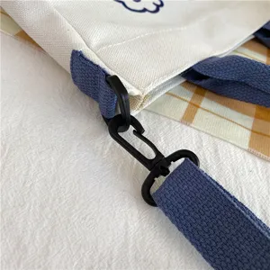 Canvas tote bag detail showing durable blue strap and black hook buckle, casual style.