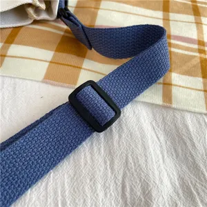 Canvas bag shoulder strap detail view, featuring durable blue woven fabric and adjustable buckle.