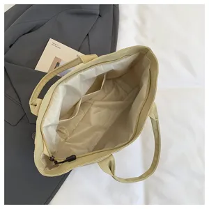 Minimalist beige canvas tote bag with zipper closure and inner pockets for daily work.