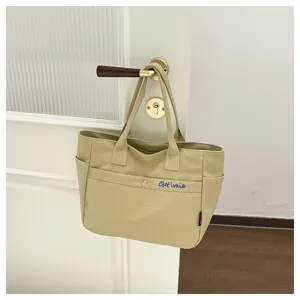 Canvas tote bag detail view showing front embroidered pocket and sturdy handles, minimalist style.