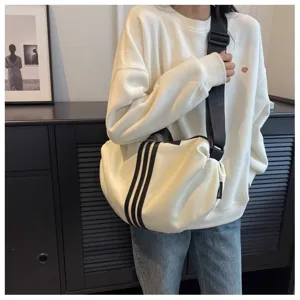 Detailed view of large capacity white crossbody bag with black stripes and wide shoulder strap.