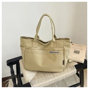 Canvas tote bag detail view, highlighting durable beige fabric and spacious front pocket.
