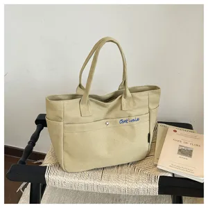 Detailed view of large capacity beige canvas tote bag, casual solid color shoulder handbag.