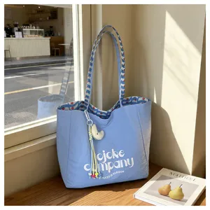 Vista dettagliata della borsa tote in tela azzurra con manici a righe, sfondo accogliente.