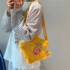 Yellow star canvas crossbody bag detail showcasing cute cartoon print and plush star pendant.