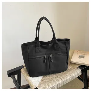 Black canvas tote bag with front zipper pockets, stylish casual commuter handbag for daily use.