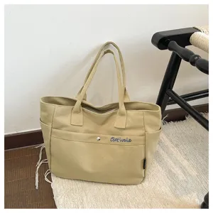 Detailed view of the casual khaki canvas tote bag with embroidery pocket and sturdy handles.